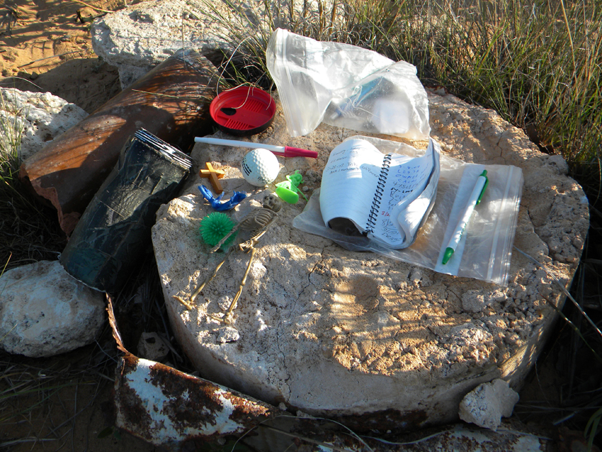 Above are the displayed contents of a 'geocache' the author discovered in the lower left corner of the Texas Panhandle. The concrete chunks are the destroyed remains of the survey marker.